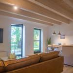 Wohn- und Essbereich mit Holzbalkendecke, Sofa, TV und Blick auf Terrasse.