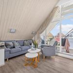 Wohnzimmer mit Sofa, Sessel und Balkonzugang.