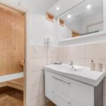 Badezimmer mit Waschbecken, Spiegel und Blick in die Sauna.