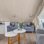 Wohnzimmer mit Sofa, Tischen und Balkonzugang.