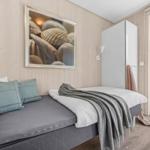 Schlafzimmer mit Bett, Wandbild und Glastür zum Garten.