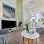 Wohnbereich mit Kamin, TV und Küchenbereich unter Dachschrägen.
