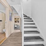 Treppenhaus mit grauen Stufen, angrenzende Bade- und Schlafzimmer.