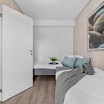 Schlafzimmer mit zwei Betten, Holzwänden und Wandbildern.