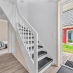 Treppenhaus mit Blick auf einen roten Anbau und Schlafzimmer mit Bett und Wandbild.