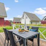Terrasse mit Tisch und Stühlen. Hintergrund: mehrere Häuser und Gras.