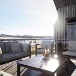 Terrasse mit Sitzgruppe und Tisch. Blick auf Windkraftanlage und Landschaft.