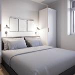 Schlafzimmer mit Bett, Kleiderschrank und Fenster. An der Wand hängen drei Bilder.