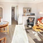 Living and dining area with orange sofa, wooden table, and white furniture.
