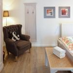 A bedroom with bed, armchair, coat hooks, and window.