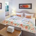 Bedroom with double bed, nightstands, and window. Towels are on the bed.