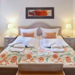 Double bed with patterned bedspread, two nightstands with lamps, and wall art above headboard.