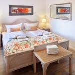A bedroom with a double bed, two nightstands, a mirror, and wooden floor.