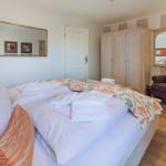 A bedroom with a double bed, wardrobe, and armchair.