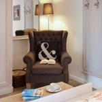 A brown armchair with cushion and book stands next to a wardrobe.