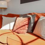 Orange sofa with cushions and floor lamp in a living room.