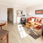 Living and dining area with orange sofa, wooden table, and TV.