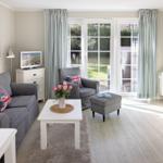 Living room with gray sofa, white furniture, and garden view.