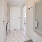 Hallway with white doors, tiled floor, and mirror on the wall.