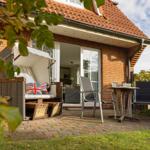 Terrace with seating and view into the house. Garden area with plants and stone paving.