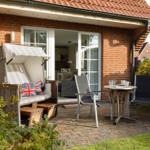 Terrace with lounger, table and chairs in front of a brick house.