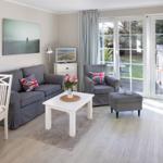 Living room with sofa, armchair, and table. Door leads to the terrace.