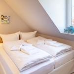 Zimmer mit Doppelbett, Fenster und Holzsideboard