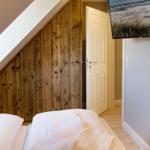 Schlafzimmer mit Holzwand, Bett und Wandbild