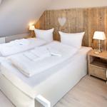 Schlafzimmer mit Doppelbett, Holzpaneelen und Nachttischen.