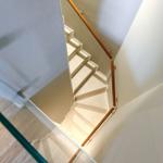 Helle Treppe mit Holzgeländer und Glasbrüstung führt in den Obergeschossbereich.