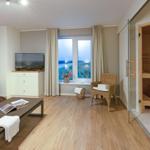 Wohnraum mit Sauna, TV, Fensterblick und Sitzgelegenheiten.