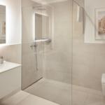 Moderne Badezimmer mit Dusche, Waschbecken und Toilette. Wandbild und Badewanne sind sichtbar.