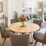 Runder Esstisch mit Stühlen und Blumen in Wohnzimmer mit Sofa und Sitzgelegenheit.
