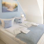Schlafzimmer mit Doppelbett, blauer Wand und Fenster mit Blick.
