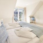 Schlafzimmer mit Doppelbett, Fenster und Kleiderschrank.