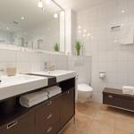 Badezimmer mit zwei Waschbecken, Spiegelschrank, Toilette und Badematten.