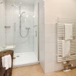 Dusche mit Glaswand, Handtuchhalter und Heizkörper an der Wand.