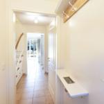 Flur mit Garderobe, Treppenhaus und Blick in Wohnbereich.