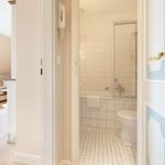 Badezimmer mit Badewanne und Dusche. Blick in Schlafzimmer mit Sofa und Fenster.