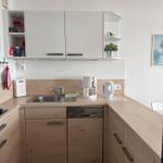 Küche mit Holzfronten, Spüle, Kaffeemaschine und Kühlschrank.