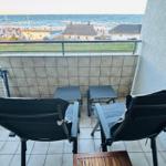 Balkon mit zwei Stühlen und Tisch, Blick auf Meer und Strand.