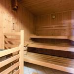 Sauna mit Holzbanken und Thermometer an der Wand.