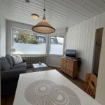 Wohnzimmer mit Sofa, TV und Esstisch mit Platzdecken.