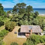 Haus mit Terrasse und Garten, umgeben von Bäumen, mit Blick auf das Meer.