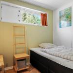Ein Schlafzimmer mit Bett, Holzregal und Fenster. Wandfarbe cremeweiß und hellgrün.