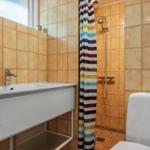 Badezimmer mit Waschbecken, Dusche und Toilette. Wandfliesen und buntes Duschvorhang.