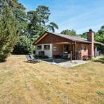 Haus mit Terrasse, Garten und Liegestühlen umgeben von Bäumen.