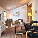 Wohnzimmer mit Sofa, Sesseln, Tisch und Fernseher an der Wand.