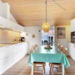 Küche mit Essbereich, weißer Einbauküche, Holzdecke und Tisch mit Tischdecke.