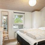 Schlafzimmer mit Bett, Fenster und Waschbecken. Holzdecke und weiße Wände.